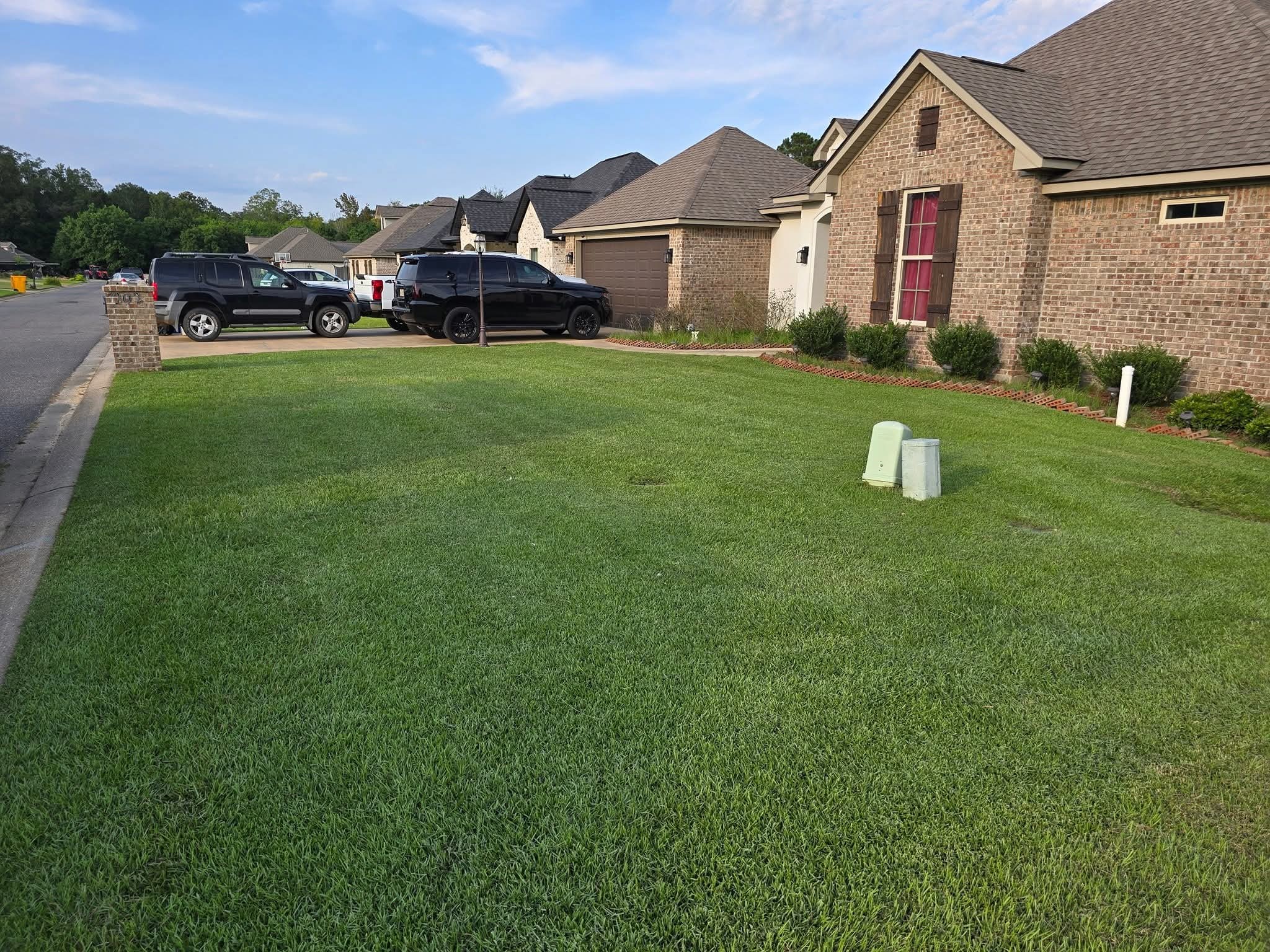 Freshly mowed front lawn of a brick home with a clean curb edge