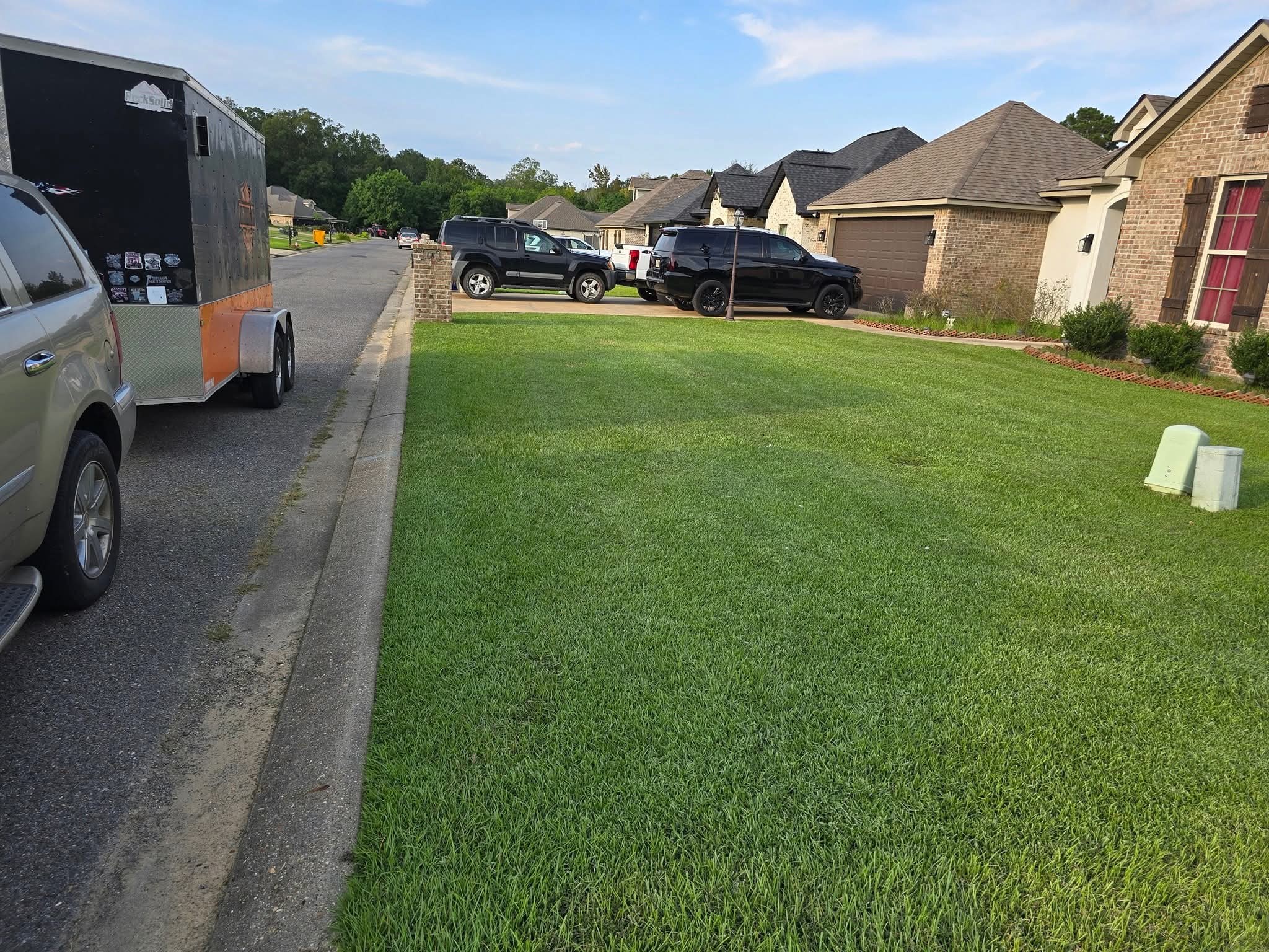 The black and orange Ross and Co trailer parked beside a finished lawn